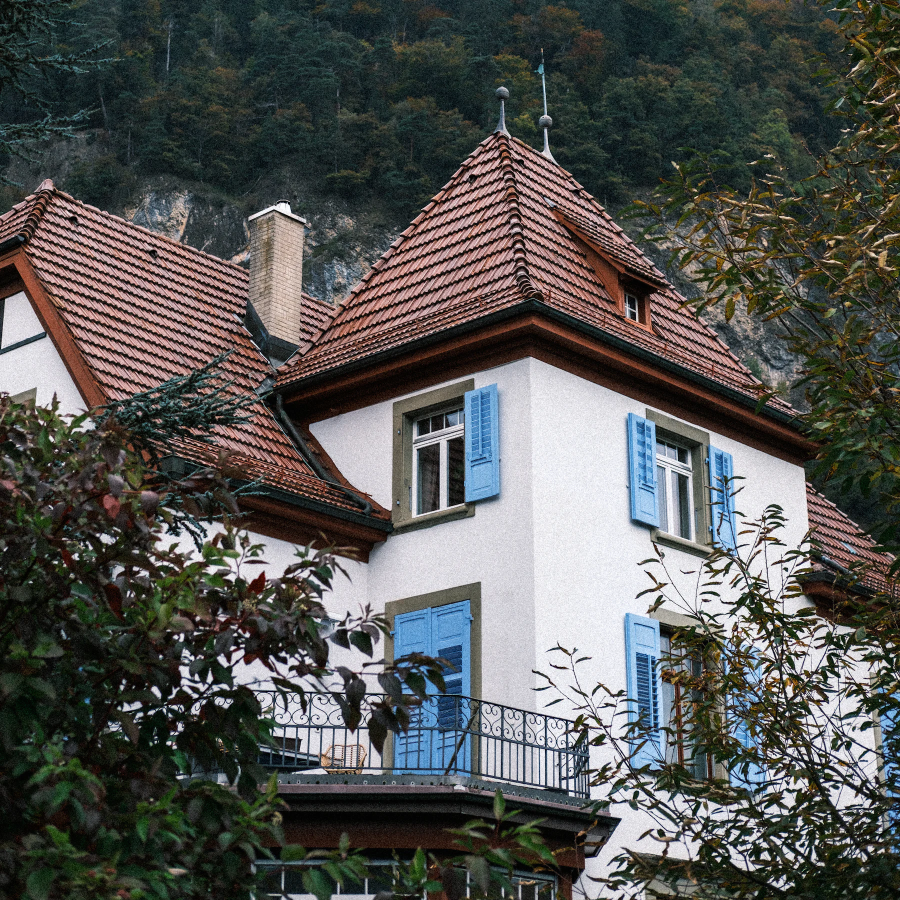Façade crépie blanche et volets bleus d’une maison à Interlaken, en Suisse